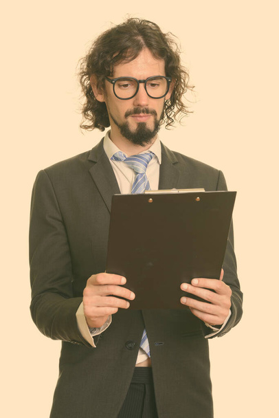 Studio shot of handsome bearded businessman with curly hair in suit isolated against white background - 写真・画像