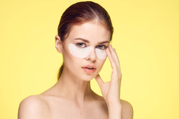 woman with bare shoulders and punchy rejuvenation skin care yellow background - Foto, immagini