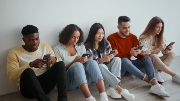 Verslaving door sociale media. Groep van jonge multi-etnische mensen web surfen op smartphones, het negeren van echte communicatie - Video
