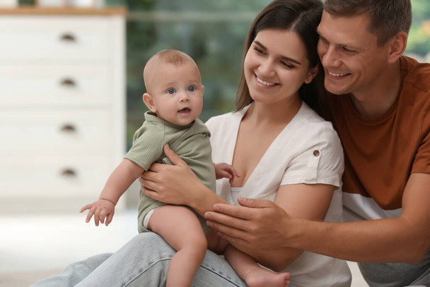 Portrait of happy family with their cute baby at home - Foto, Bild