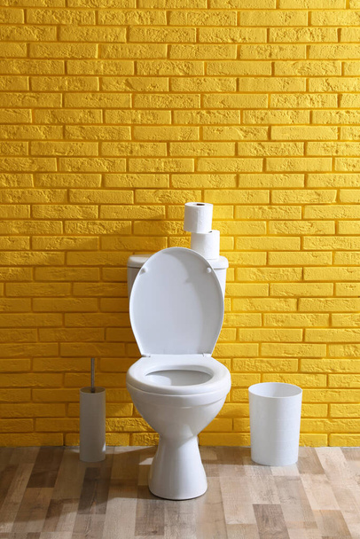 Simple bathroom interior with toilet bowl near yellow brick wall indoors. Home design - Foto, Imagem