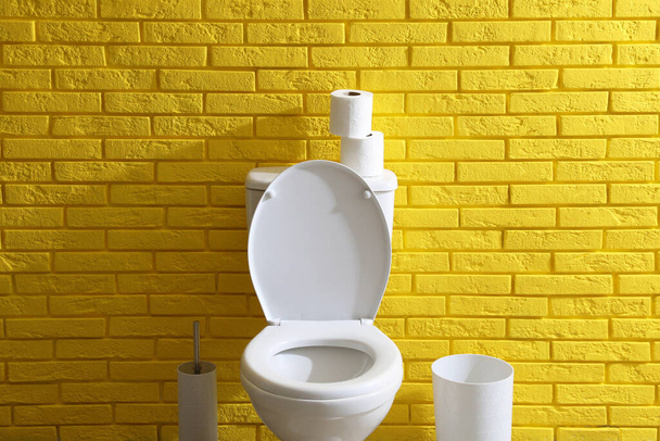 Simple bathroom interior with toilet bowl near yellow brick wall indoors. Home design - Φωτογραφία, εικόνα