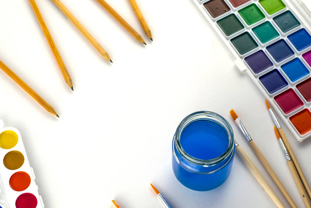 Aquarellfarben pinseln ein Glas Wasser und Bleistifte auf einen weißen Hintergrund. Hochwertiges Foto - Foto, Bild