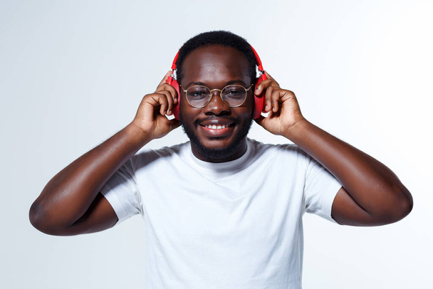 Een slimme leidinggevende draagt een gouden bril en luistert naar muziek terwijl hij aan een gelukkige herinnering denkt. Hij draagt een wit shirt. Hij heeft een baard.. - Foto, afbeelding