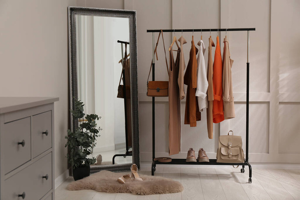 Rack with stylish women's clothes and mirror in dressing room - Φωτογραφία, εικόνα