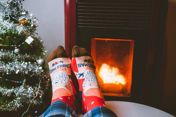 Red christmas socks with christmas message next to a fireplace and a christmas tree - Photo, image