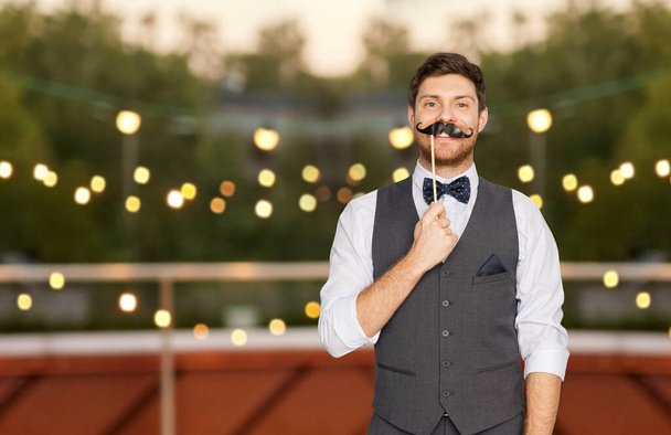 happy man with fake mustache at rooftop party - Фото, изображение