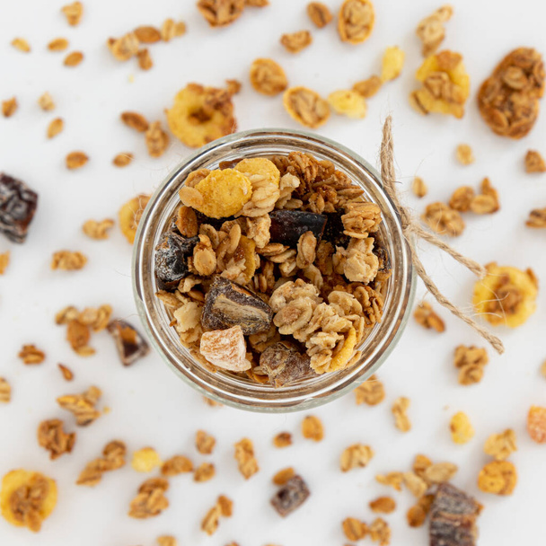 rapea granola lasipurkissa eristetty valkoisella taustalla, ylhäältä, terveellinen aamiainen käsite - Valokuva, kuva