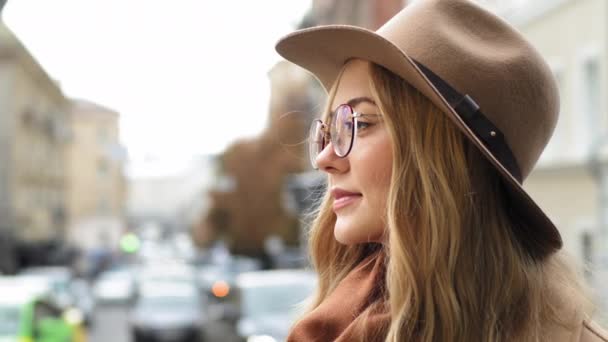 Detailní profil běloška dívka student atraktivní mladá žena myšlení stojící na ulici ve městě dáma zamyšleně při pohledu do dálky venku boční pohled tisíciletá blondýna žena s kloboukem a brýlemi - Záběry, video
