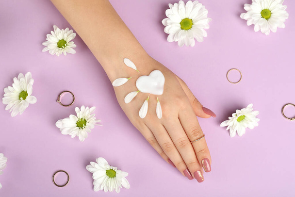 Konzept der Handpflege auf lila Hintergrund mit Blumen - Foto, Bild
