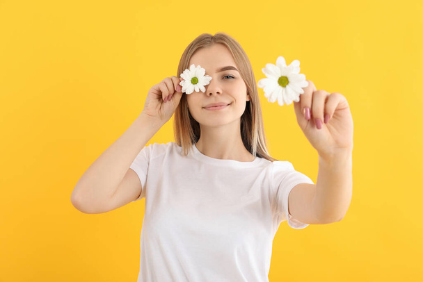 Ελκυστικό κορίτσι με λουλούδια σε κίτρινο φόντο - Φωτογραφία, εικόνα