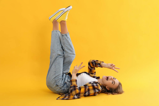 Young attractive girl in checkered shirt on yellow background - Photo, Image
