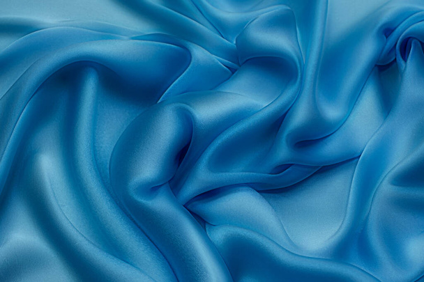 Zbliżenie tekstury naturalnej niebieskiej tkaniny lub materiału w tym samym kolorze. Tekstura tkaniny z naturalnej bawełny, jedwabiu lub wełny lub lnu materiału włókienniczego. Niebieskie tło płótna. - Zdjęcie, obraz