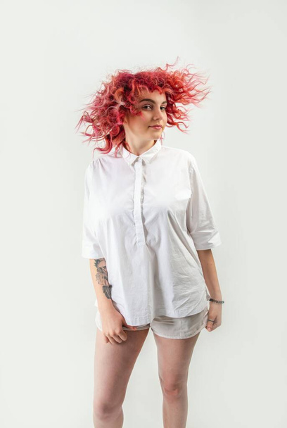beautiful red-haired girl posing on a white background in a white shirt with emotions on her face - Фото, изображение