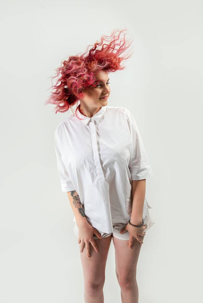 beautiful red-haired girl posing on a white background in a white shirt with emotions on her face - Fotó, kép