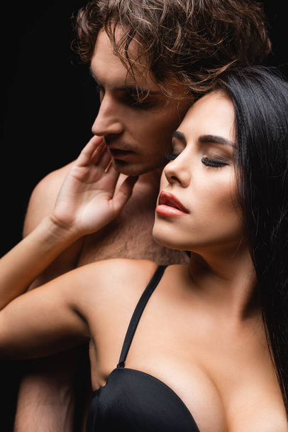 brunette woman touching face of shirtless man isolated on black  - Photo, Image