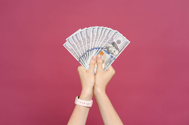 Γυναίκα χέρι κρατώντας χρήματα δολάρια σε ροζ φόντο - Φωτογραφία, εικόνα