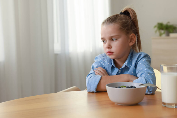 Nettes kleines Mädchen, das sich weigert, zu Hause zu frühstücken, Platz für Text - Foto, Bild
