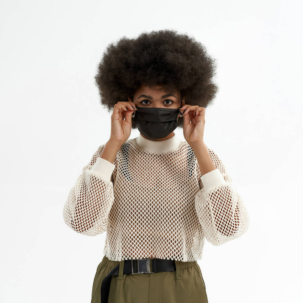 Μαύρη γυναίκα διορθώνει ιατρική μάσκα στο πρόσωπό της - Φωτογραφία, εικόνα