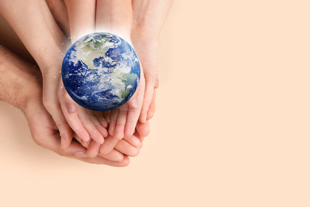 World in our hands. Top view of parents and kid holding digital model of Earth on beige background, space for text  - Foto, afbeelding