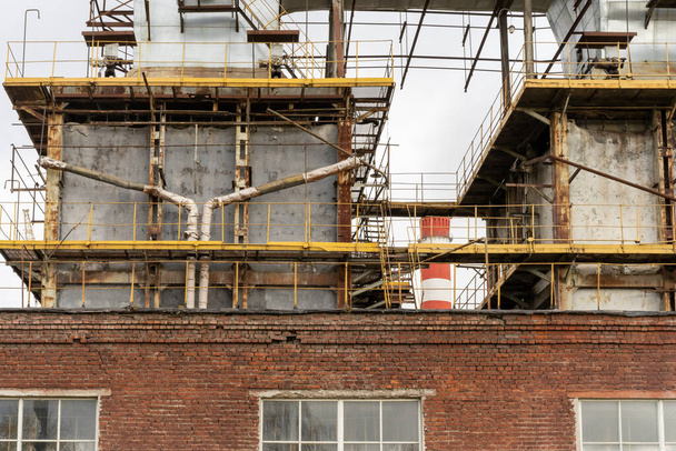 Photo of metal pipes next to a thermoelectric plant with big chimneys. Factory. Brick building. - Fotó, kép