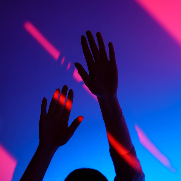Женщина рукой жест с открытой рукой над модой голубой и розовый стены, неоновый красный свет на запястье.  - Фото, изображение