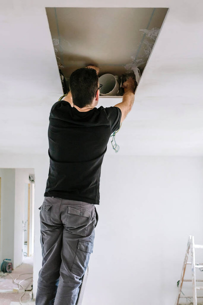 Homme préparant l'installation de hotte sur le plafond de la cuisine - Photo, image