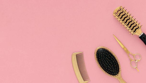 Herramientas de peluquería dorada tijeras peines sobre fondo rosa. Plantilla horizontal con accesorios de peluquería en la esquina y espacio para copiar. - Foto, Imagen