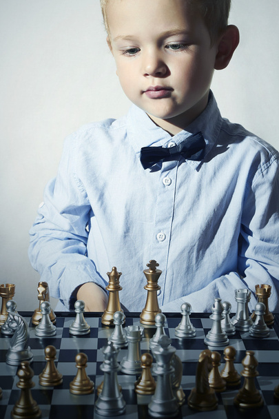 Petit garçon jouant aux échecs.Enfant mart.enfants de la mode.5 ans Enfant de genie.Petit enfant génie. Jeu intelligent.Chessboard
 - Photo, image