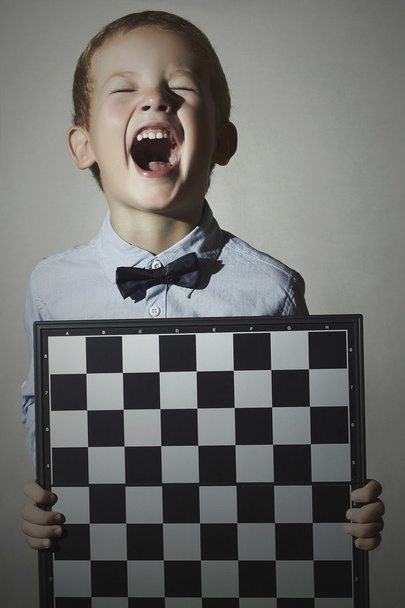 Menino engraçado com tabuleiro de xadrez. Crianças Emotion.Smile.laughter
 - Foto, Imagem