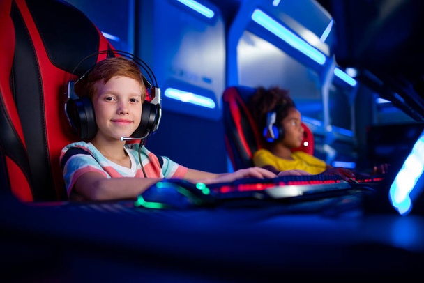 Portrait of professional young gamer with headset playing computer video games and enjoying entertainment industry. - Photo, image