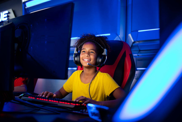 Portrait of excited African American girl with headset playing video games on computer in game room. - Photo, image