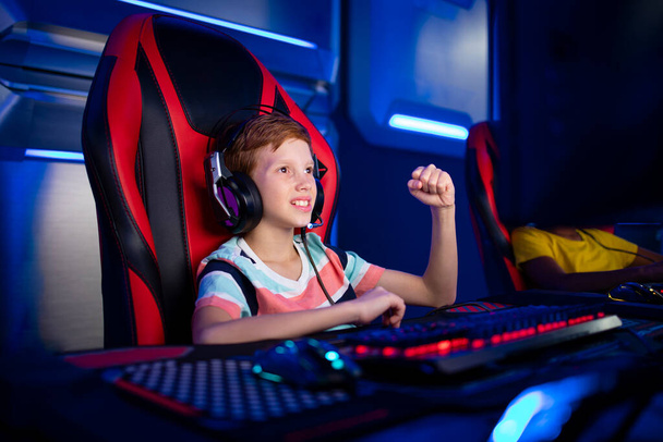 Professionelle junge Gamer Junge mit der Faust für die erfolgreiche Beendigung der Mission in Computervideospiel. - Foto, Bild