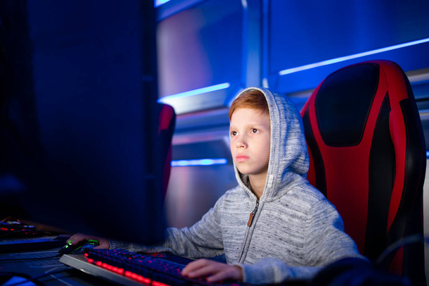 Ritratto di ragazzo caucasico che gioca ai videogiochi sul computer nella sala giochi. Dipendenza dei bambini da giochi virtuali e intrattenimento. - Foto, immagini
