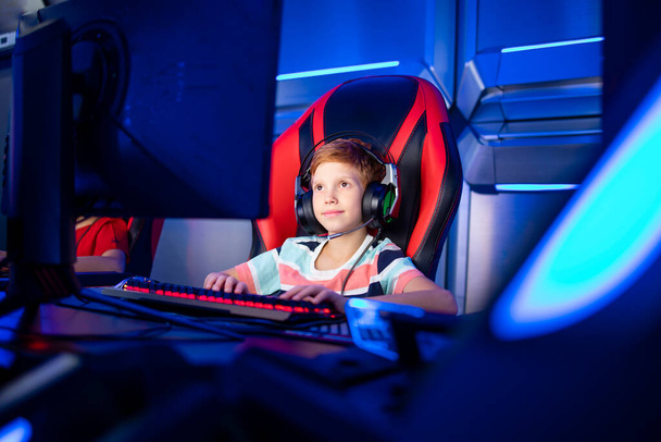 Professional gamer with headset playing or streaming online video games on computer. Children addicted to entertainment industry. - Фото, зображення