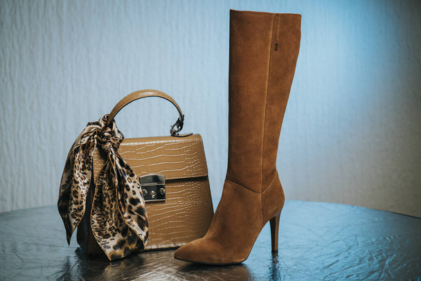 A closeup of a female handbag and high heels on a table - Фото, изображение