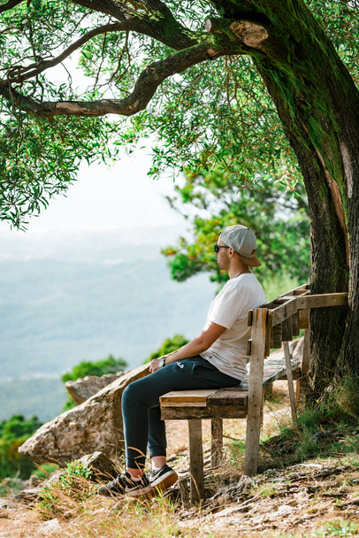 VIANA DO CASTELO, PORTUGAL - Oct 02, 2021: A man sitting on a bench on top of a hill - Φωτογραφία, εικόνα