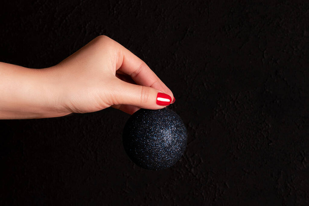 Hand with blue Christmas ball and red nails - Foto, Imagem
