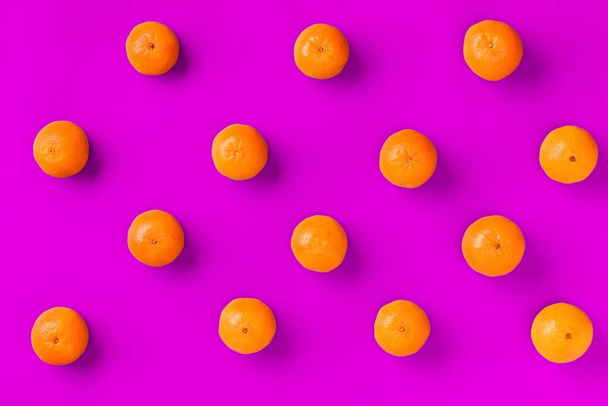 Fruit pattern of fresh orange tangerine or mandarin on lilac background. Flat lay, top view. Pop art design, creative summer concept. Citrus in minimal style. - 写真・画像