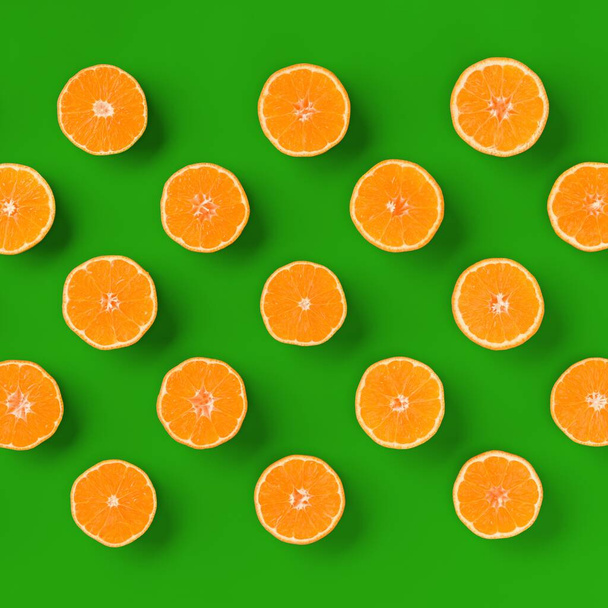 Fruit pattern of fresh orange tangerine or mandarin over green background. Flat lay, top view. Pop art design, creative summer concept. Citrus in minimal style. - Foto, afbeelding