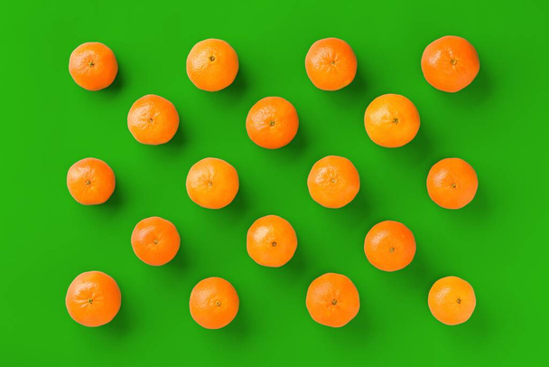 Fruit pattern of fresh orange tangerine or mandarin on green background. Flat lay, top view. Pop art design, creative summer concept. Citrus in minimal style. - Zdjęcie, obraz