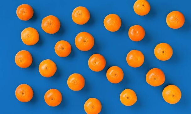 Fruit pattern of fresh orange tangerine or mandarin on blue background. Flat lay, top view. Pop art design, creative summer concept. Citrus in minimal style. - Fotoğraf, Görsel
