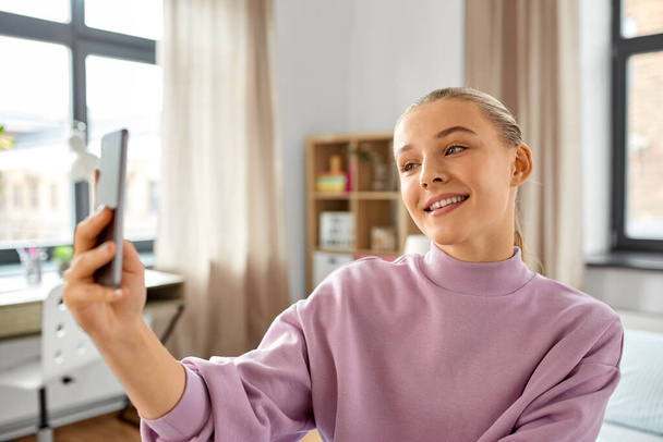 happy girl with smartphone taking selfie at home - Fotó, kép
