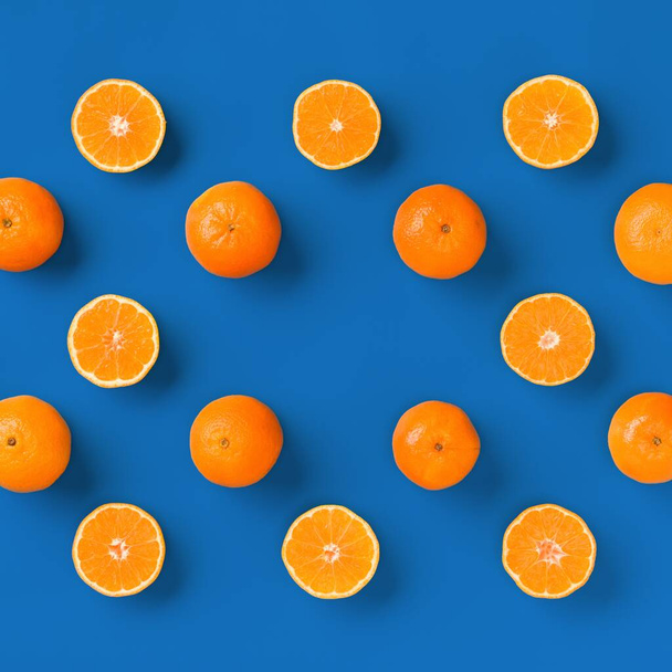 Fruit pattern of fresh orange tangerine or mandarin on blue background. Flat lay, top view. Pop art design, creative summer concept. Citrus in minimal style. - Photo, image