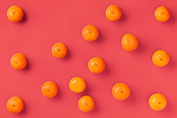 Fruit pattern of fresh orange tangerine or mandarin on living coral background. Flat lay, top view. Pop art design, creative summer concept. Citrus in minimal style. - 写真・画像