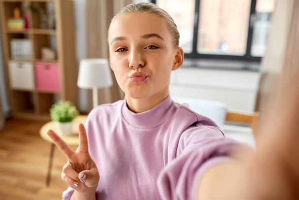 girl taking selfie at home and showing peace - Fotografie, Obrázek