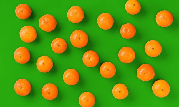 Fruit pattern of fresh orange tangerine or mandarin on green background. Flat lay, top view. Pop art design, creative summer concept. Citrus in minimal style. - Фото, изображение