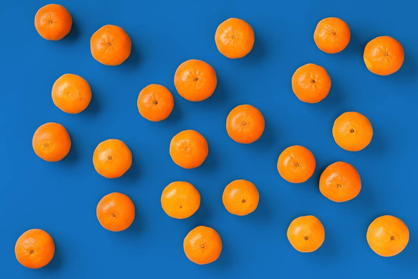 Fruit pattern of fresh orange tangerine or mandarin on blue background. Flat lay, top view. Pop art design, creative summer concept. Citrus in minimal style. - Foto, Bild