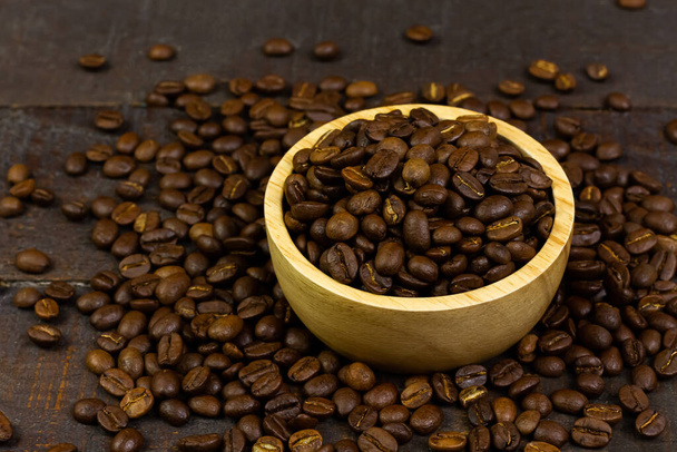 kávová zrna v dřevěné misce na dřevěné pozadí. - Fotografie, Obrázek