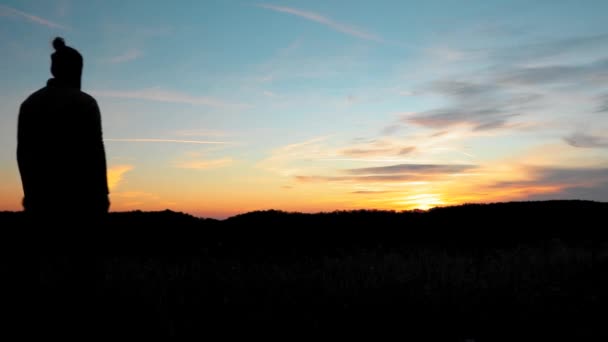 Η σιλουέτα ενός ανθρώπου που απολαμβάνει το όμορφο ηλιοβασίλεμα σε ένα λόφο κατά τη διάρκεια του φθινοπώρου  - Πλάνα, βίντεο